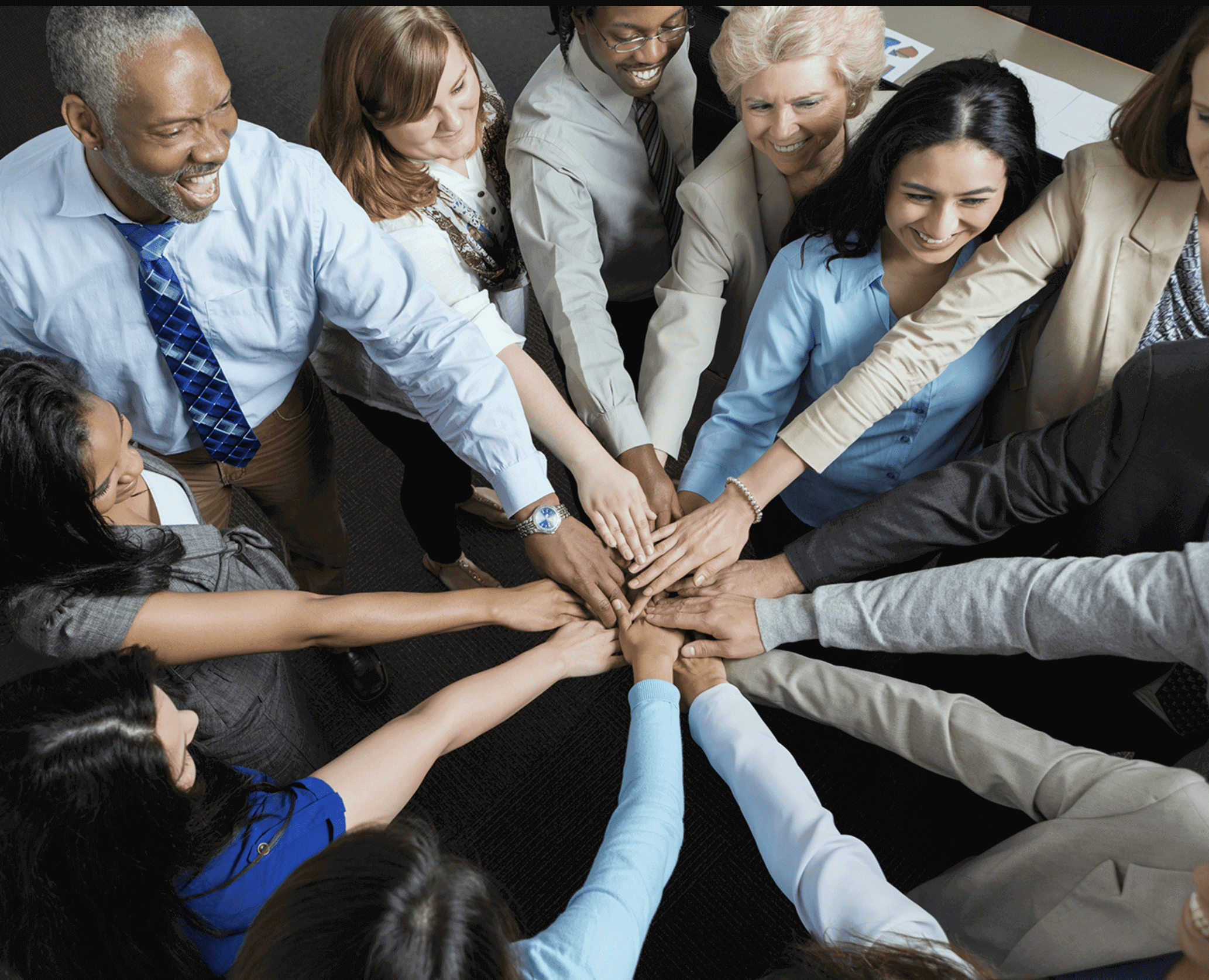 Diverse group joining hands in unity and teamwork.