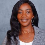 Professional woman smiling in business attire against gray background.