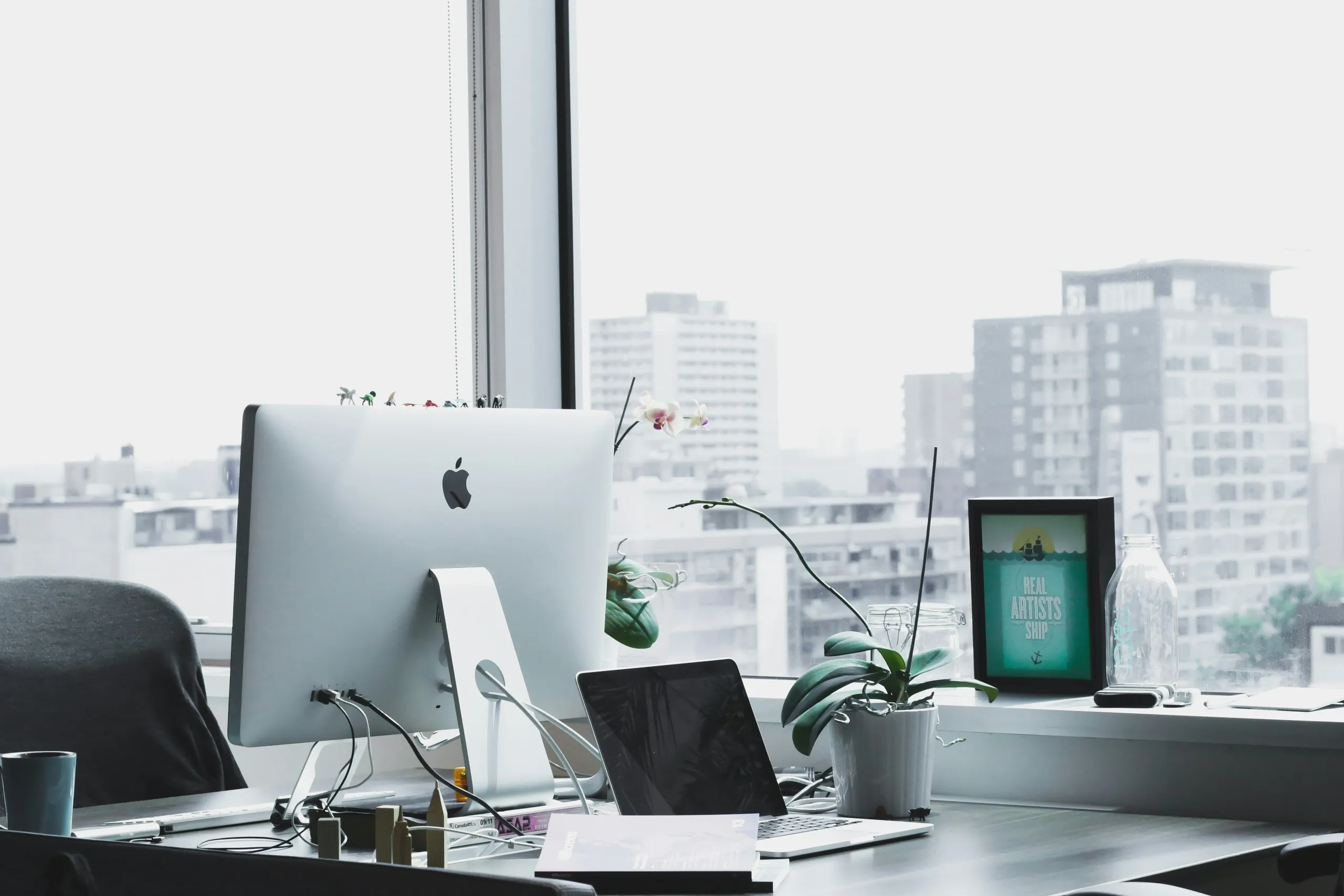 Modern office desk with computer and plants.