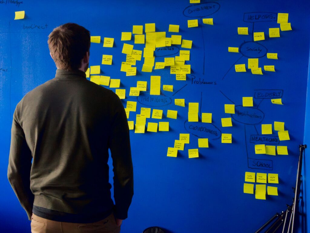 Man observing sticky notes on blue wall.