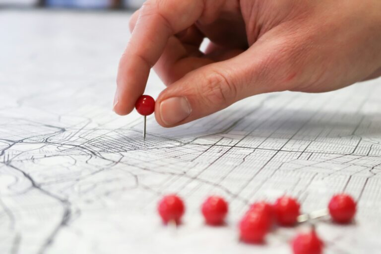 Hand placing red pin on a map.