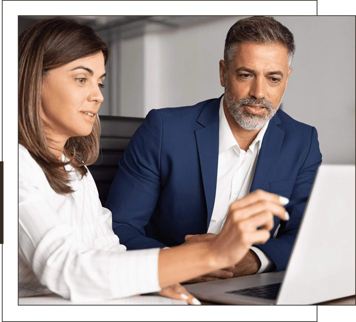 Two professionals collaborating over a laptop in an office setting.