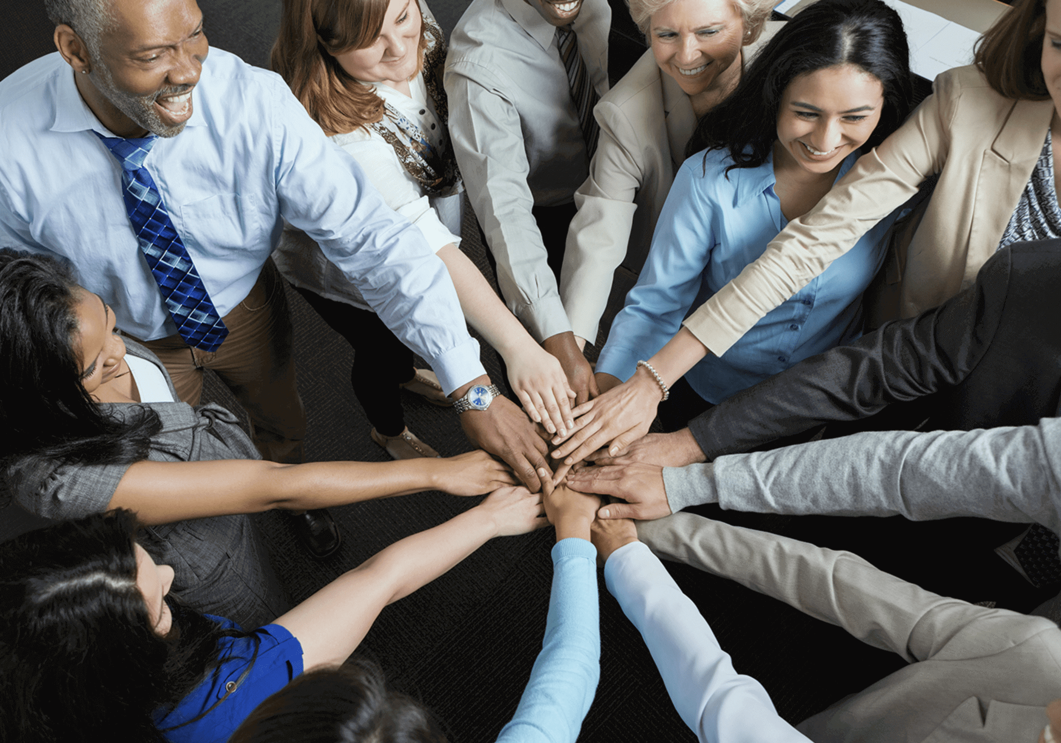 Diverse group joining hands in unity and teamwork.